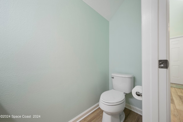 bathroom featuring wood-type flooring, lofted ceiling, and toilet