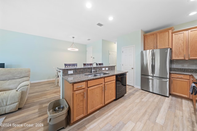 kitchen featuring pendant lighting, sink, stainless steel refrigerator, dishwasher, and light hardwood / wood-style floors