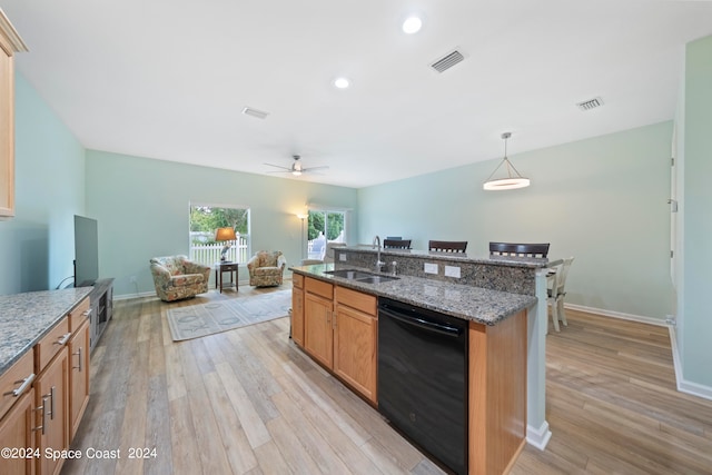 kitchen with light wood-type flooring, black dishwasher, sink, decorative light fixtures, and light stone countertops