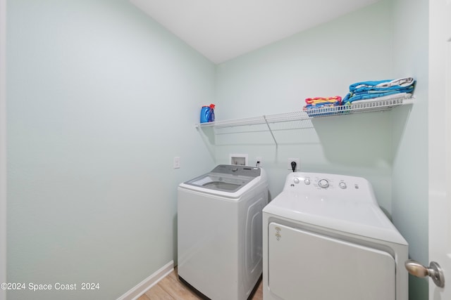 washroom with light hardwood / wood-style floors and washing machine and dryer