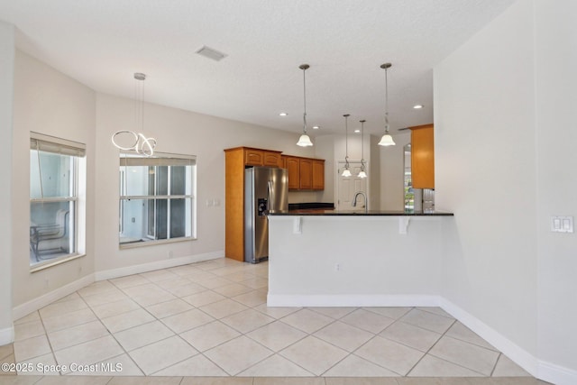 929 Hialeah St, Rockledge, FL 32955 - kitchen featuring stainless steel fridge, an inviting chandelier, dark countertops, a peninsula, and brown cabinetry