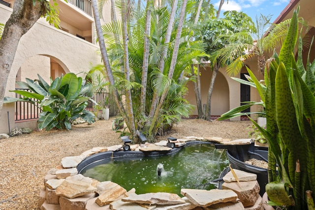 view of yard with a balcony and a small pond