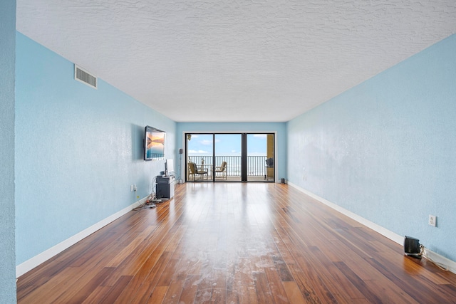 unfurnished living room featuring a textured ceiling and hardwood / wood-style flooring