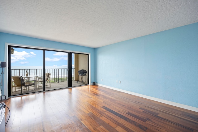 empty room with a water view, hardwood / wood-style flooring, and a textured ceiling