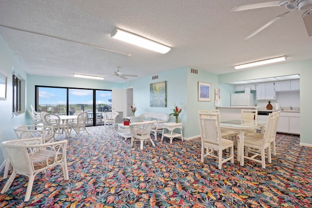 dining room with sink, ceiling fan, carpet floors, and a textured ceiling