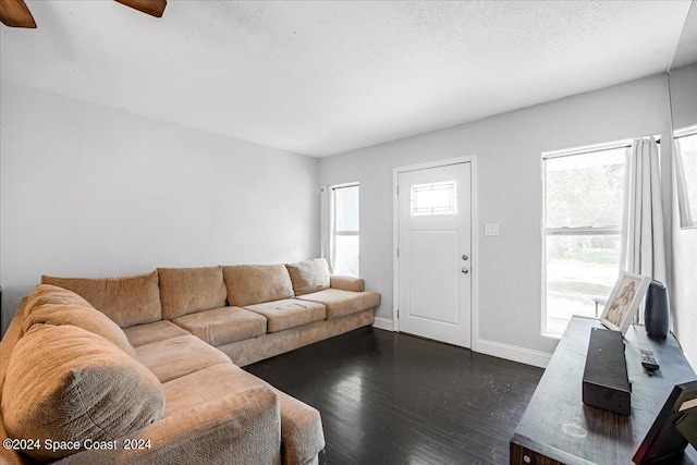 living room with a textured ceiling, ceiling fan, and dark hardwood / wood-style flooring