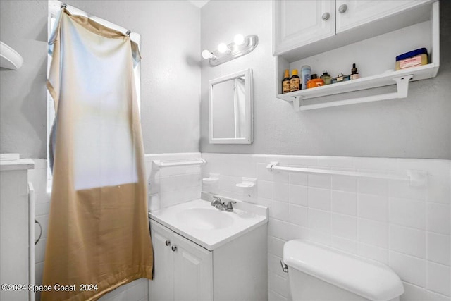 bathroom with vanity, tile walls, and toilet