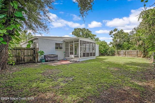 back of house featuring a patio, a yard, and a sunroom