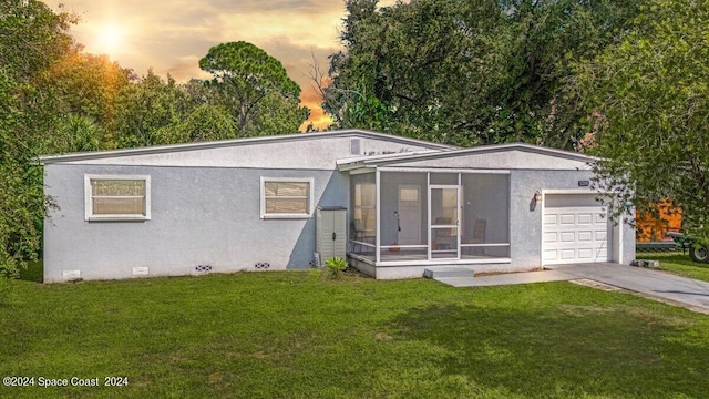 view of front facade featuring a sunroom, a yard, and a garage