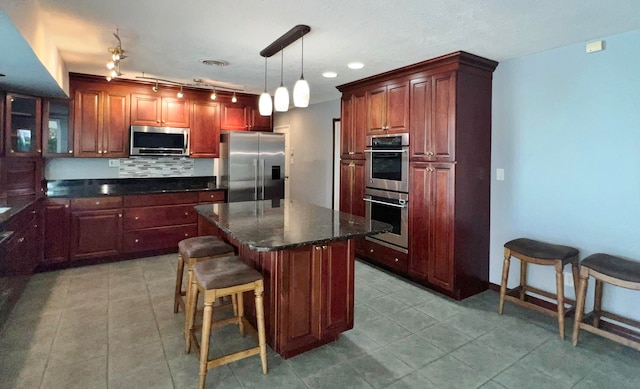 kitchen featuring a breakfast bar, a center island, hanging light fixtures, decorative backsplash, and appliances with stainless steel finishes