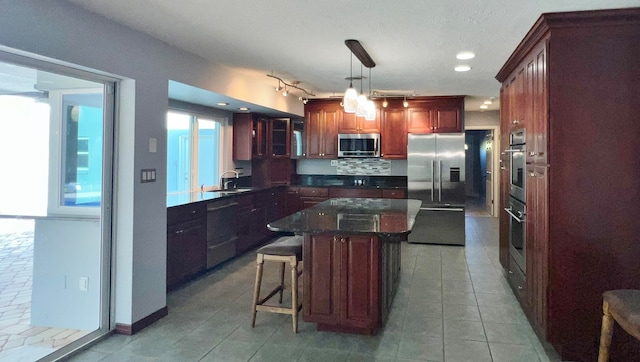 kitchen featuring tasteful backsplash, a kitchen island, decorative light fixtures, stainless steel appliances, and a kitchen bar