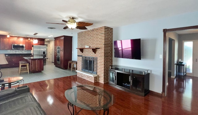 living room with a fireplace, ceiling fan, and hardwood / wood-style flooring