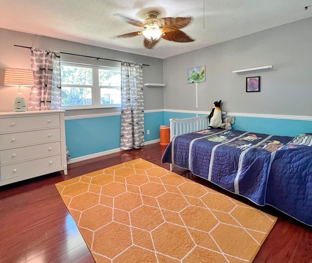 bedroom with ceiling fan, dark hardwood / wood-style floors, and a textured ceiling