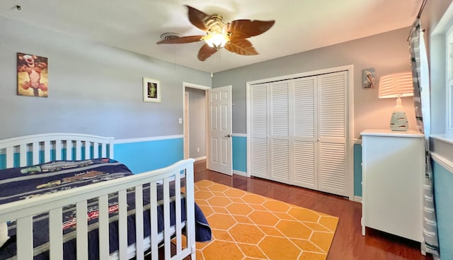 bedroom with dark wood-type flooring, ceiling fan, and a closet