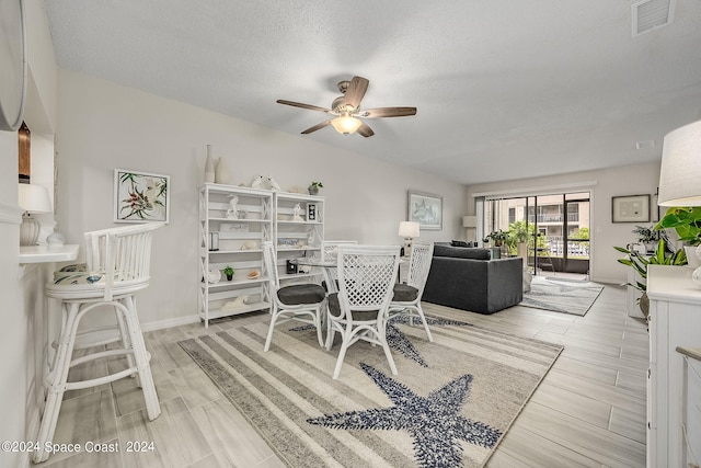 dining space featuring a textured ceiling, ceiling fan, and light hardwood / wood-style flooring