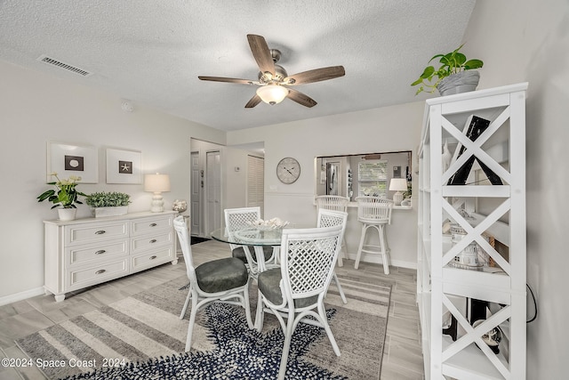 dining space featuring ceiling fan, a textured ceiling, and light wood-type flooring