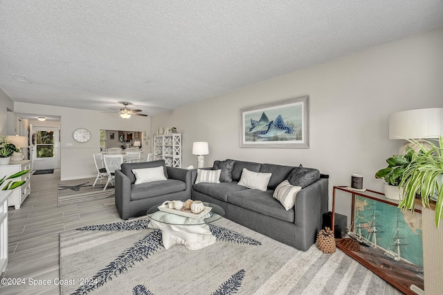 living room with a textured ceiling, ceiling fan, and light hardwood / wood-style flooring