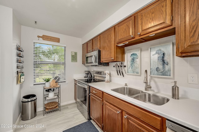 kitchen with light wood-type flooring, decorative backsplash, sink, and stainless steel appliances