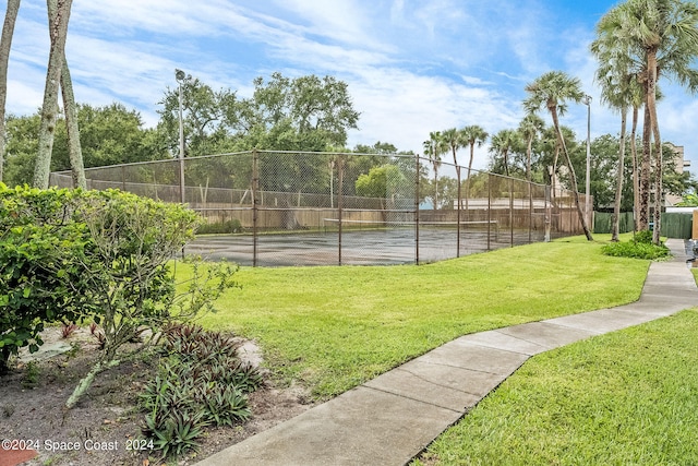 view of tennis court featuring a yard