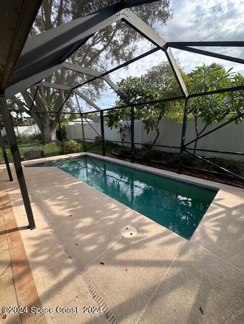 view of swimming pool featuring glass enclosure and a patio area