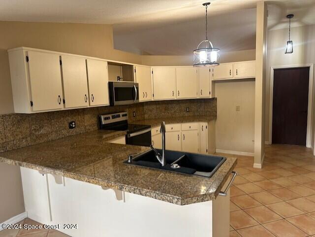 kitchen with stainless steel appliances, lofted ceiling, hanging light fixtures, and tasteful backsplash