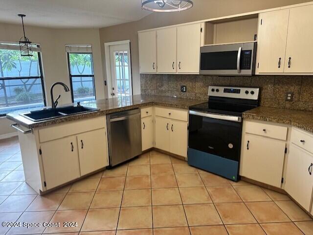 kitchen with white cabinets, sink, kitchen peninsula, backsplash, and stainless steel appliances