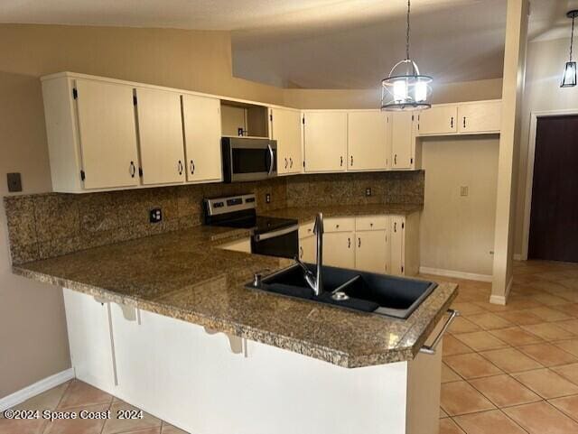 kitchen featuring kitchen peninsula, tasteful backsplash, decorative light fixtures, stainless steel appliances, and vaulted ceiling