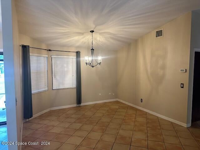 unfurnished room featuring a chandelier, vaulted ceiling, and tile patterned floors