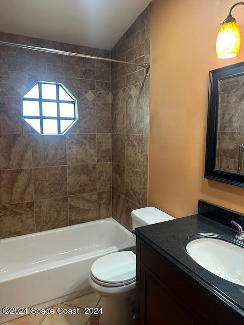 full bathroom with vanity, toilet, tiled shower / bath combo, tile patterned flooring, and vaulted ceiling