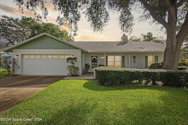 single story home featuring a lawn and a garage