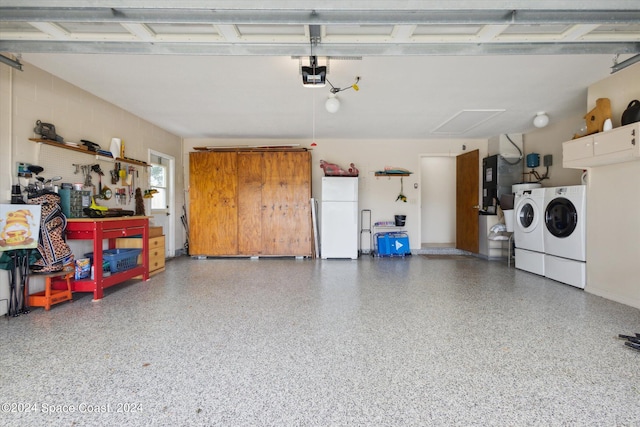 garage featuring washing machine and dryer, a garage door opener, white refrigerator, and a workshop area