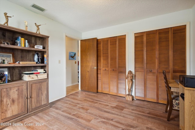 office with light hardwood / wood-style floors and a textured ceiling