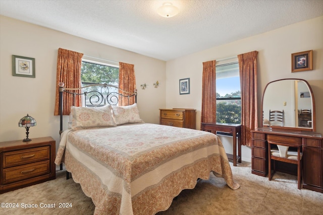 bedroom featuring light colored carpet and a textured ceiling