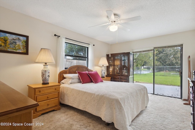 carpeted bedroom featuring access to exterior, ceiling fan, and a textured ceiling