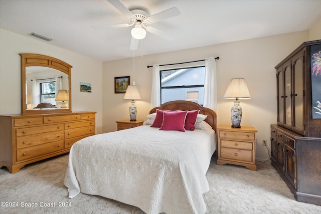 bedroom with light colored carpet, multiple windows, and ceiling fan