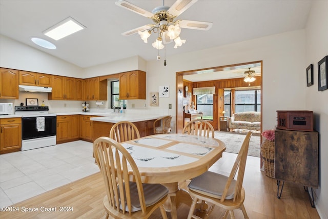 dining room with ceiling fan, vaulted ceiling, and light hardwood / wood-style floors