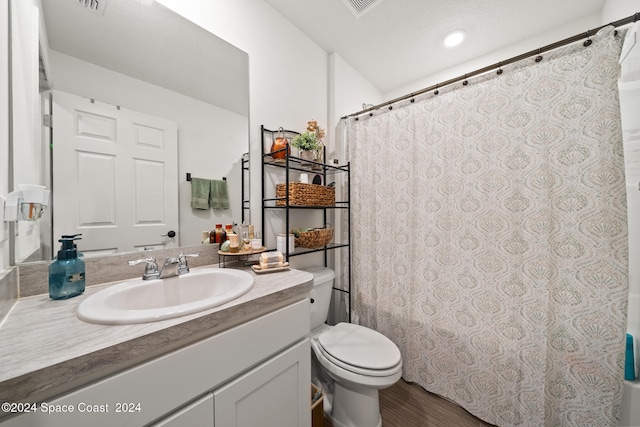 bathroom featuring hardwood / wood-style flooring, vanity, toilet, and walk in shower