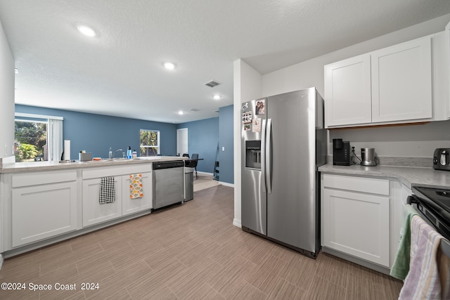 kitchen with stainless steel appliances, white cabinetry, and plenty of natural light