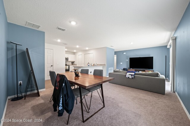 carpeted dining space featuring a textured ceiling