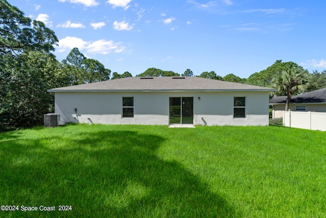 rear view of property featuring a lawn and central AC unit