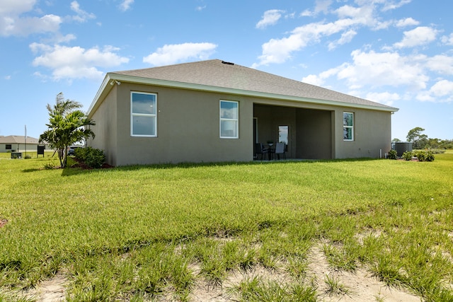 back of property featuring a lawn and central AC