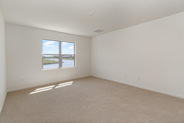 carpeted spare room featuring a water view