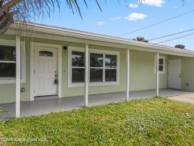 doorway to property with a lawn