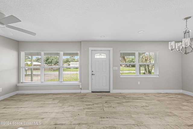 entrance foyer with a textured ceiling, light hardwood / wood-style flooring, and ceiling fan with notable chandelier