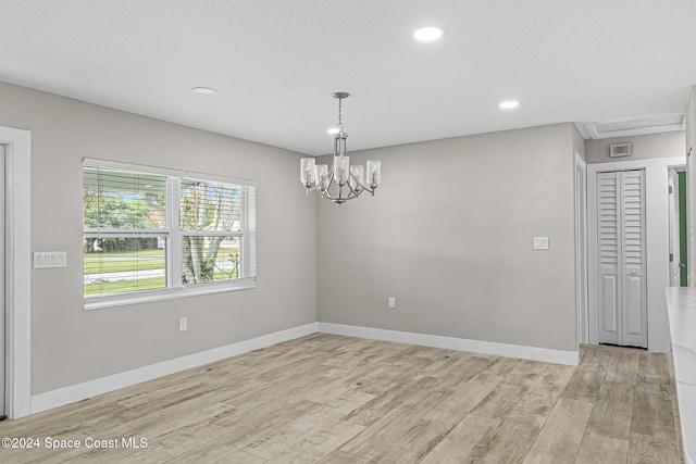 spare room featuring light hardwood / wood-style floors and a notable chandelier