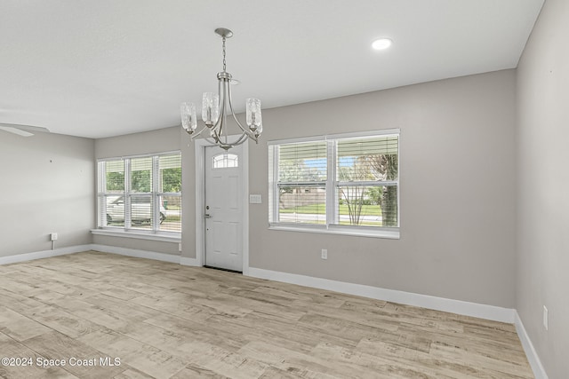 unfurnished room featuring light hardwood / wood-style floors and ceiling fan with notable chandelier