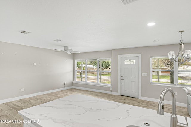 foyer entrance with light hardwood / wood-style flooring and ceiling fan with notable chandelier