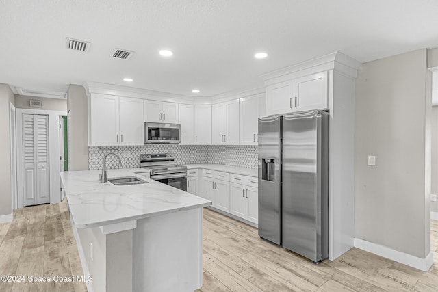 kitchen with light hardwood / wood-style floors, white cabinetry, stainless steel appliances, and sink