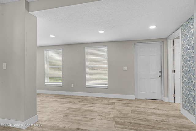 unfurnished room featuring a textured ceiling and light wood-type flooring