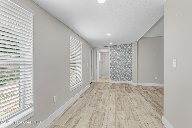 hallway featuring light hardwood / wood-style flooring and a textured ceiling